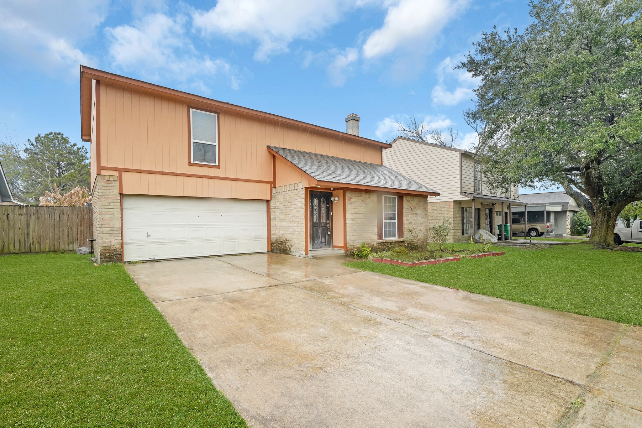 635 Walston Lane Houston, TX 77060 - Photo 2 of 24 This photo shows a two-story house with a combination of brick and orange siding. It features a two-car garage and a neatly maintained front yard with a spacious driveway. A large tree provides shade on the side, enhancing the curb appeal.