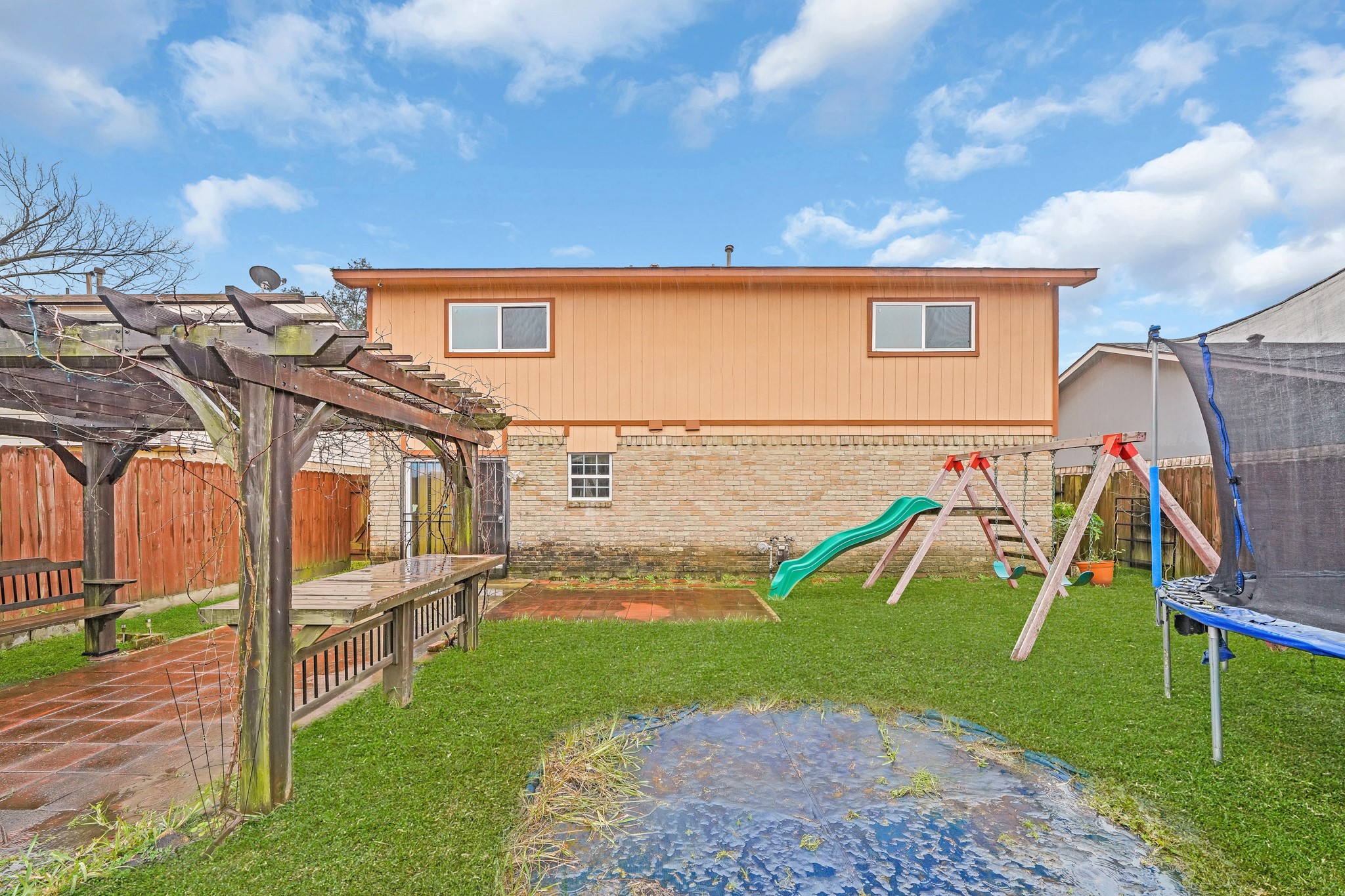 635 Walston Lane Houston, TX 77060 - Photo 24 of 24 Spacious backyard with a pergola, playset including a slide, and a trampoline, perfect for family activities and outdoor relaxation.
