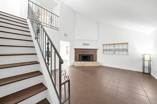 a view of an empty room with wooden floor and a fireplace