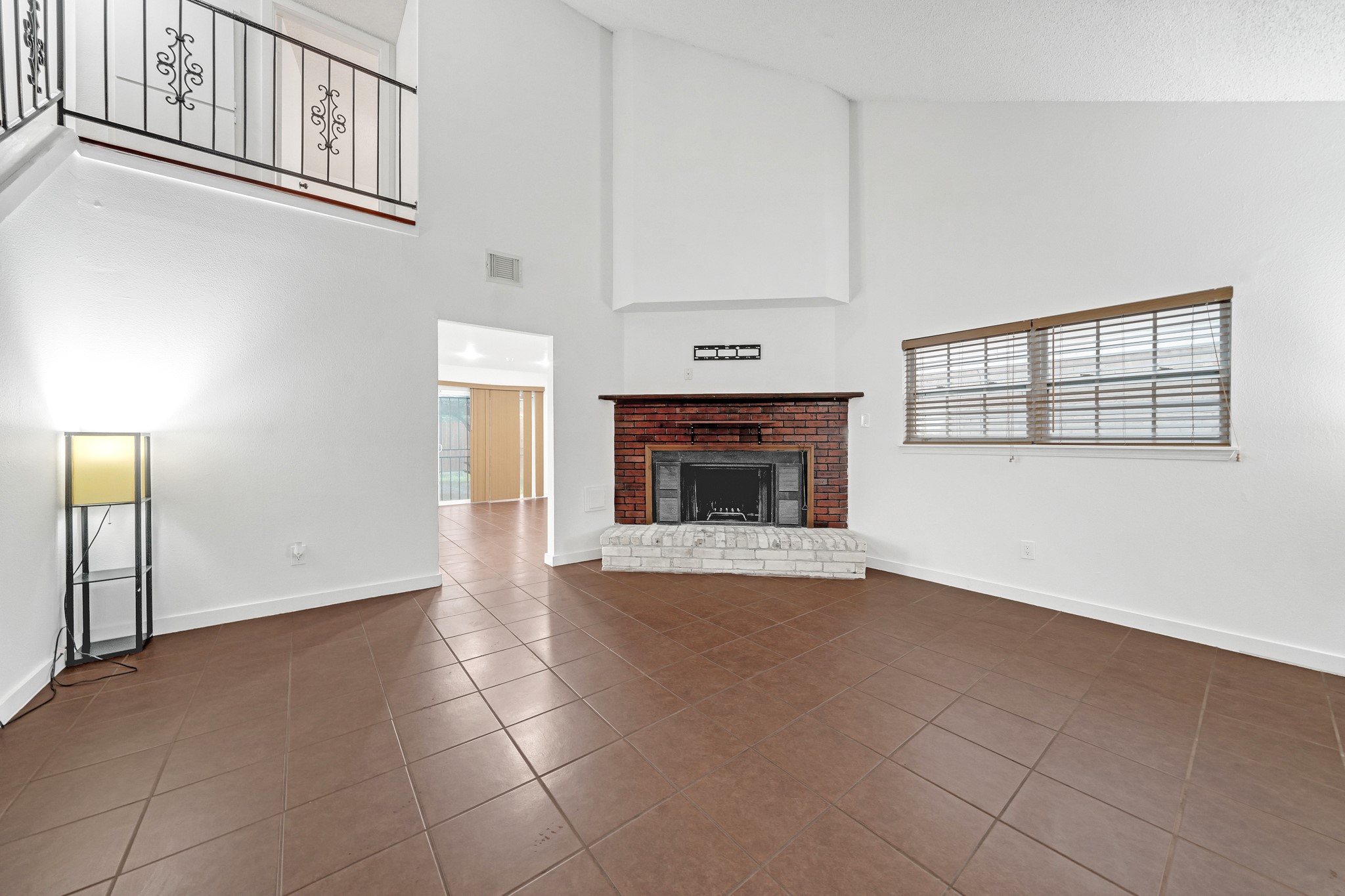 635 Walston Lane Houston, TX 77060 - Photo 6 of 24 Spacious living room with high ceilings, featuring a cozy brick fireplace. It has large windows for natural light, tiled flooring, and a modern open layout.