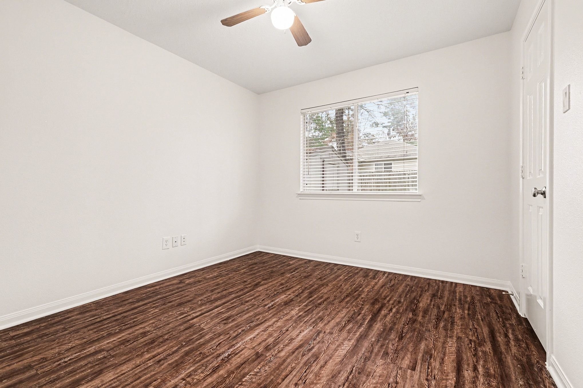 3218 Woodchuck Road Montgomery, TX 77356 - Photo 20 of 27 an empty room with wooden floor chandelier fan and windows