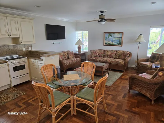 a living room with furniture a flat screen tv and kitchen view