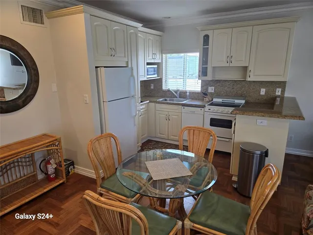 a kitchen with stainless steel appliances granite countertop a stove a sink a dining table and chairs