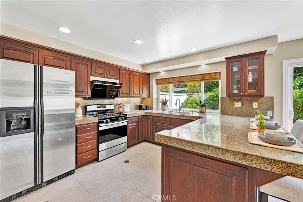 2489 Via Castillo Tustin, CA 92782 - Photo 7 of 30 a kitchen with granite countertop kitchen island stainless steel appliances a sink stove and cabinets