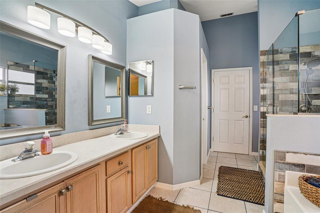 2052 Onecco Court Clermont, FL 34714 - Photo 13 of 33 a spacious bathroom with a double vanity sink a mirror and a shower