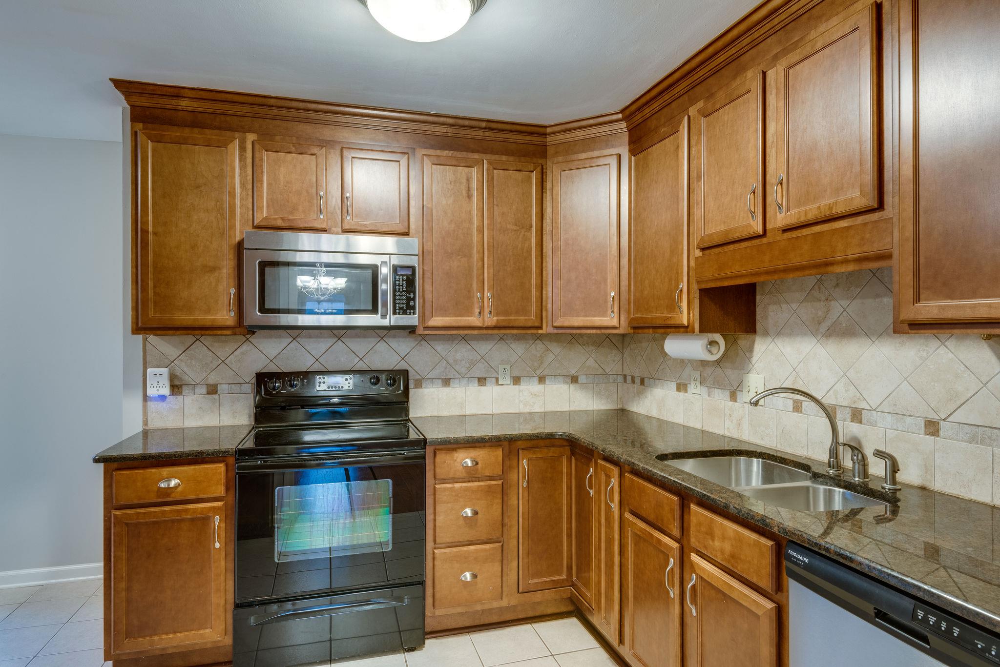 1012 General George Patton Road Nashville, TN 37221 - Photo 12 of 28 a kitchen with stainless steel appliances granite countertop a sink stove and microwave
