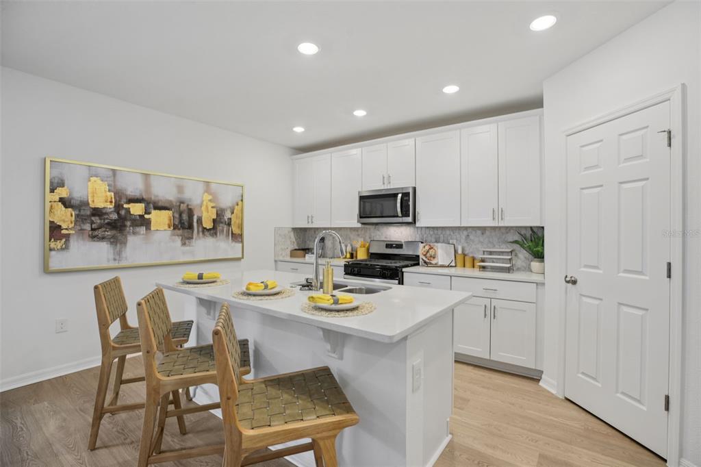 28005 Poppy Court Leesburg, FL 34748 - Photo 17 of 54 a kitchen with a dining table cabinets appliances and wooden floor