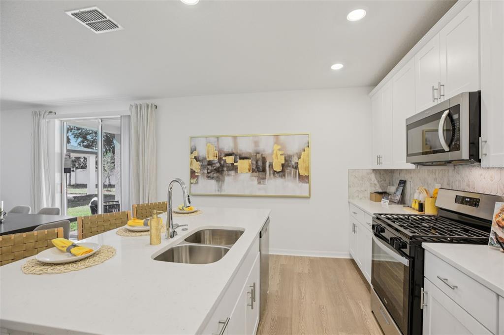 28005 Poppy Court Leesburg, FL 34748 - Photo 18 of 54 a kitchen with stainless steel appliances a stove a sink and a refrigerator