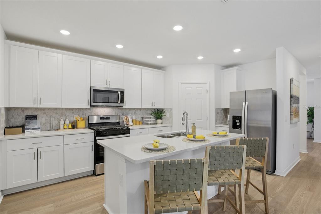 28005 Poppy Court Leesburg, FL 34748 - Photo 21 of 54 a kitchen with a sink a microwave a refrigerator and cabinets