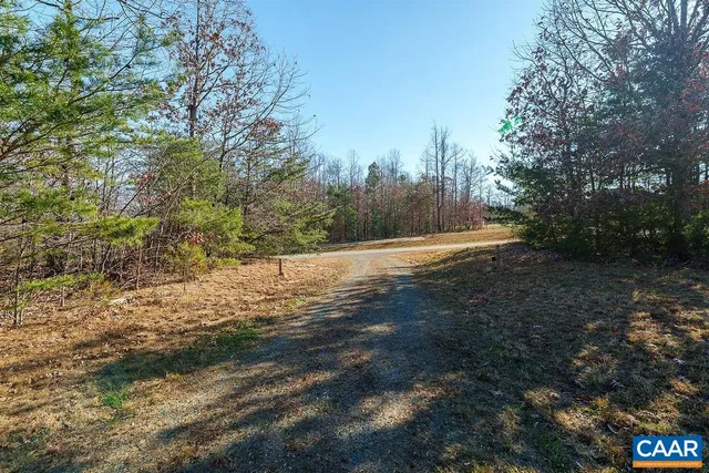 a view of dirt field with trees around