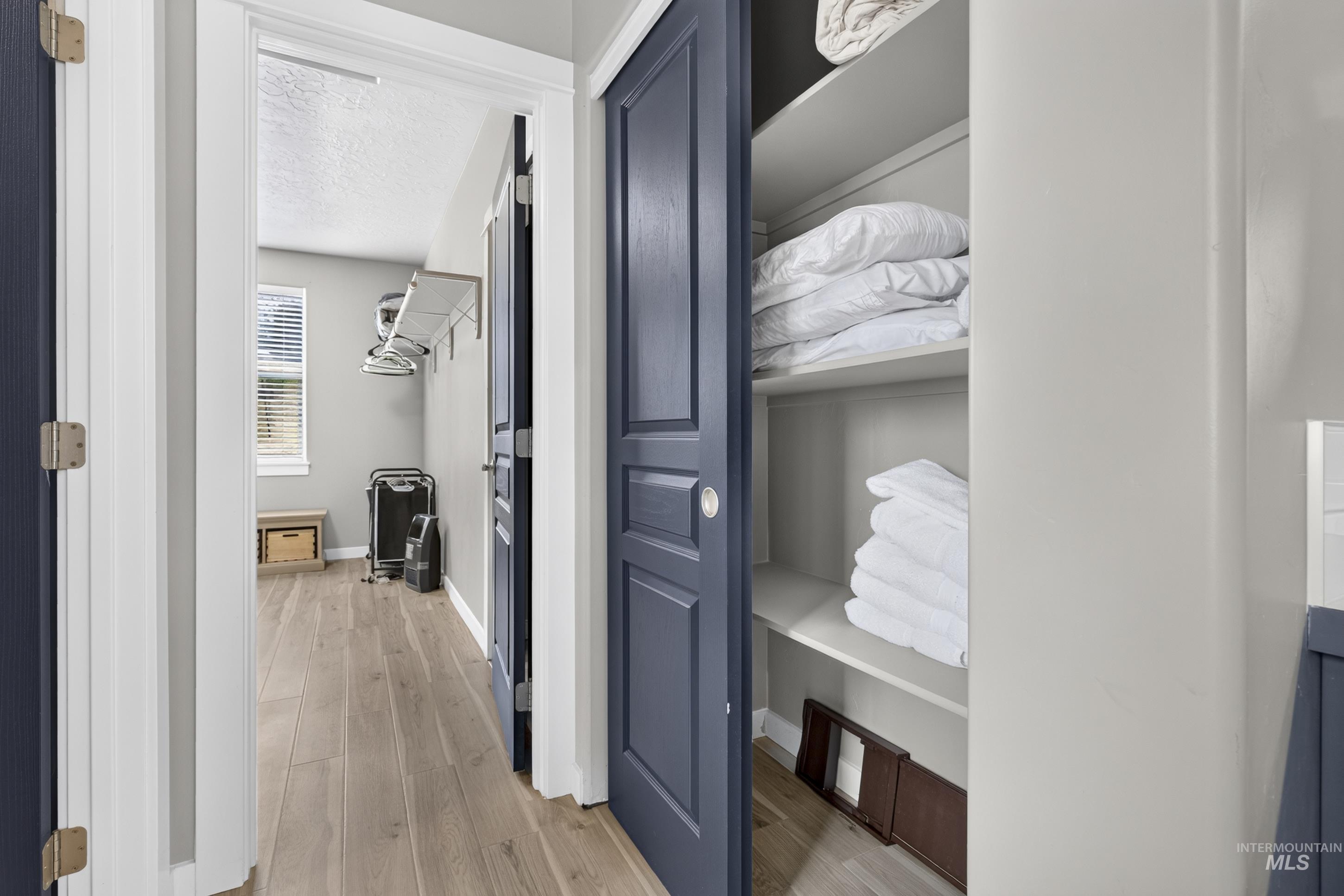 132 Mores Creek Rim Road Boise, ID 83716 - Photo 23 of 44 Wood-finish flooring throughout, a built-in laundry room shelving unit, and a built-in linen closet with shelving
