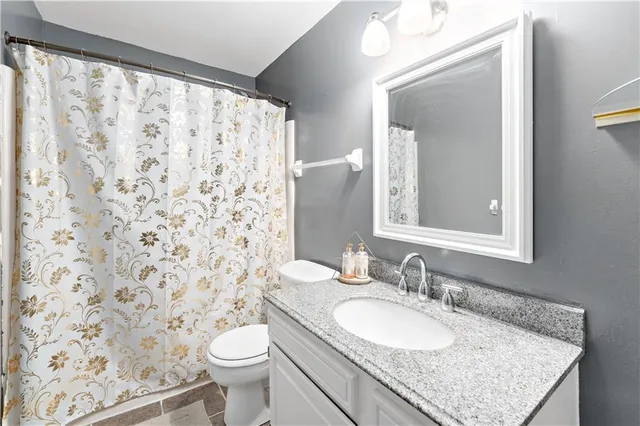 a bathroom with a granite countertop sink toilet and a mirror