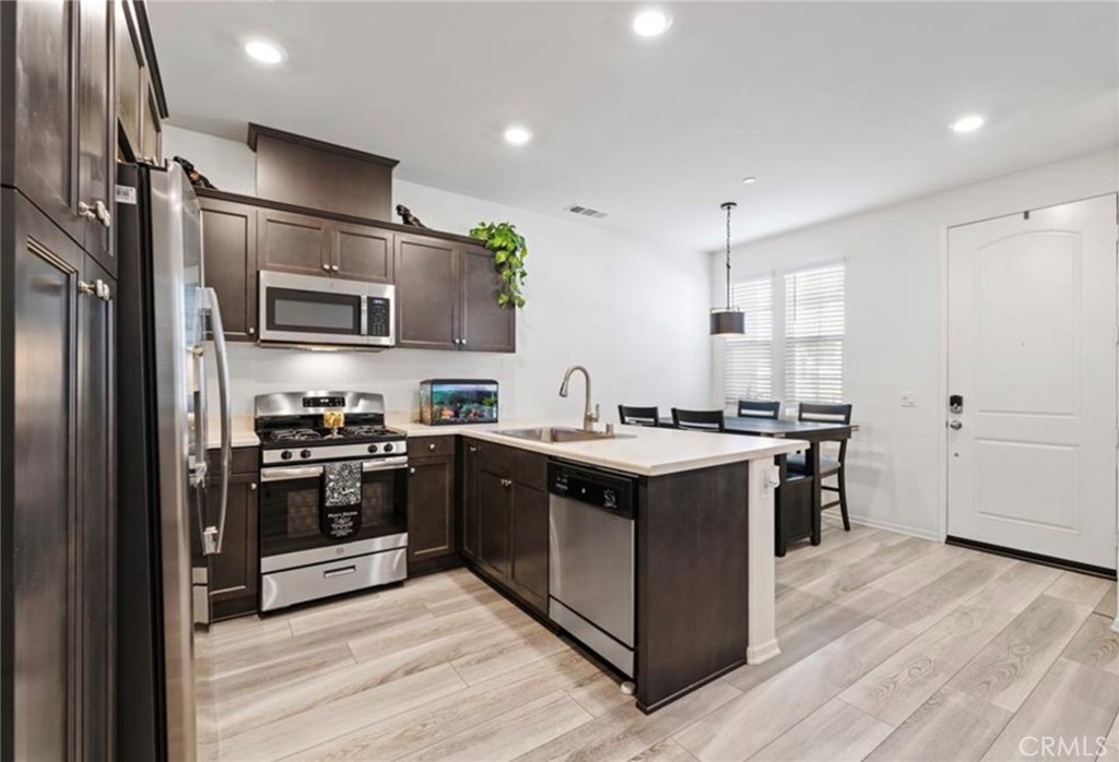 30360 Town Square Drive Menifee, CA 92584 - Photo 4 of 26 a kitchen with stainless steel appliances granite countertop a stove top oven a refrigerator and white cabinets with wooden floors