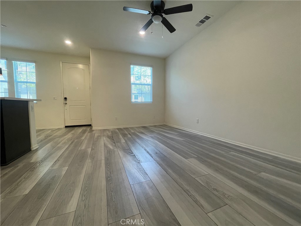 30360 Town Square Drive Menifee, CA 92584 - Photo 8 of 26 an empty room with wooden floor a ceiling fan and windows