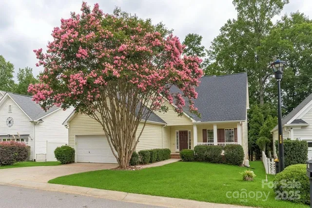 a front view of a house with a garden and tree