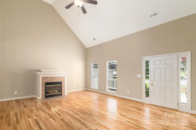 an empty room with wooden floor fireplace and windows