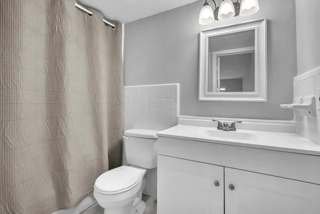 a bathroom with a toilet sink vanity and mirror