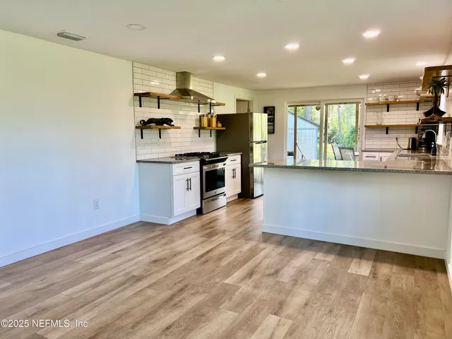 a large kitchen with stainless steel appliances granite countertop a stove sink and cabinets
