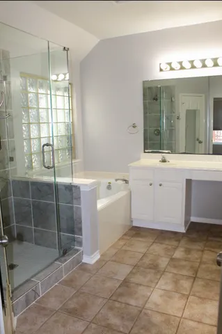 a bathroom with a tub sink and glass door shower