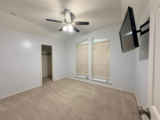 an empty room with chandelier fan and windows