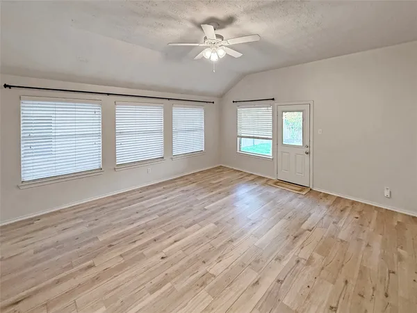 an empty room with wooden floor and windows