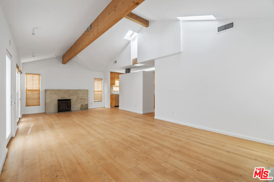 a view of empty room with wooden floor and fireplace