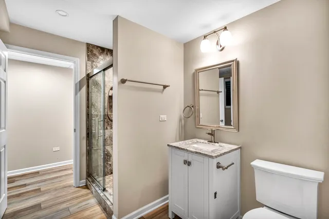 a bathroom with a granite countertop sink a toilet a mirror and shower