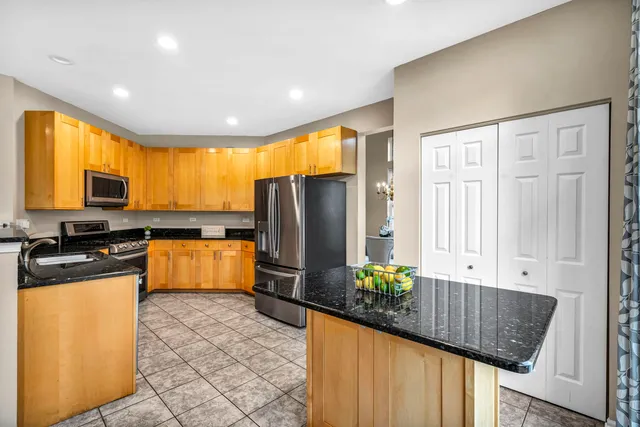 a kitchen with stainless steel appliances granite countertop a refrigerator a stove a sink dishwasher and wooden cabinets with wooden floor