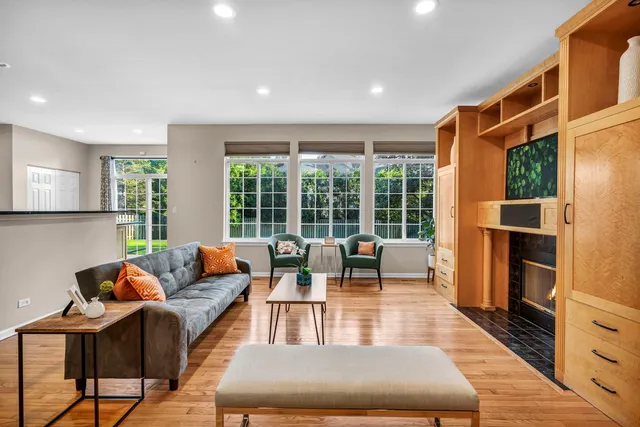 a living room with furniture a large window and wooden floor