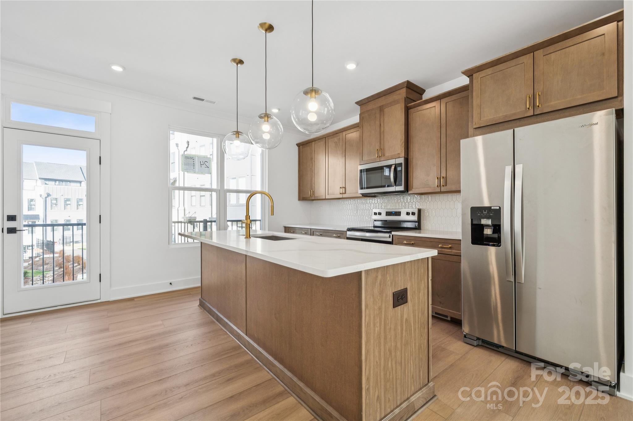 a kitchen with stainless steel appliances granite countertop a refrigerator a sink dishwasher a kitchen island with wooden cabinets and floor