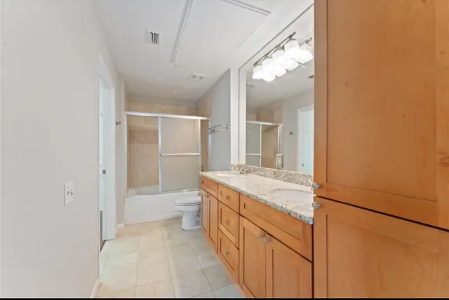 a bathroom with a granite countertop sink a toilet and shower