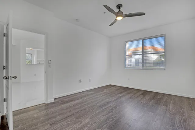 a view of empty room with wooden floor and fan