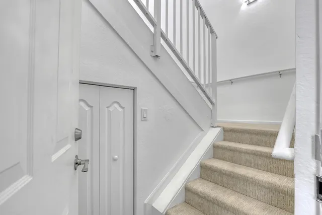 a view of staircase with white walls and white door