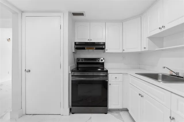 a kitchen with stainless steel appliances a sink a stove a refrigerator and cabinets