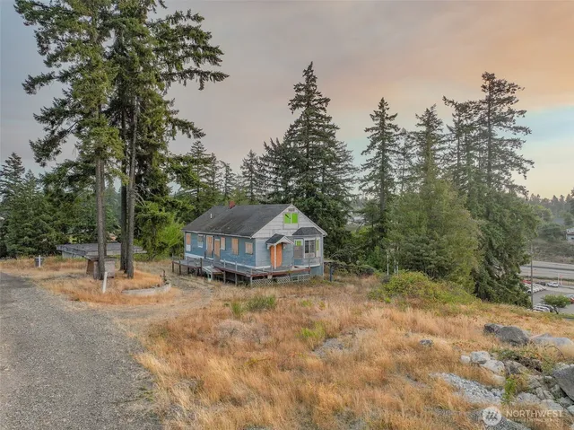 a view of a wooden house with a yard and large trees
