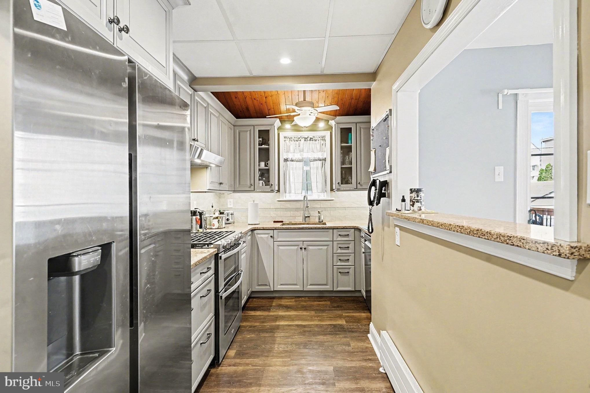 4031 Vernon Road Drexel Hill, PA 19026 - Photo 14 of 38 a kitchen with stainless steel appliances granite countertop a sink and dishwasher a refrigerator with wooden floor