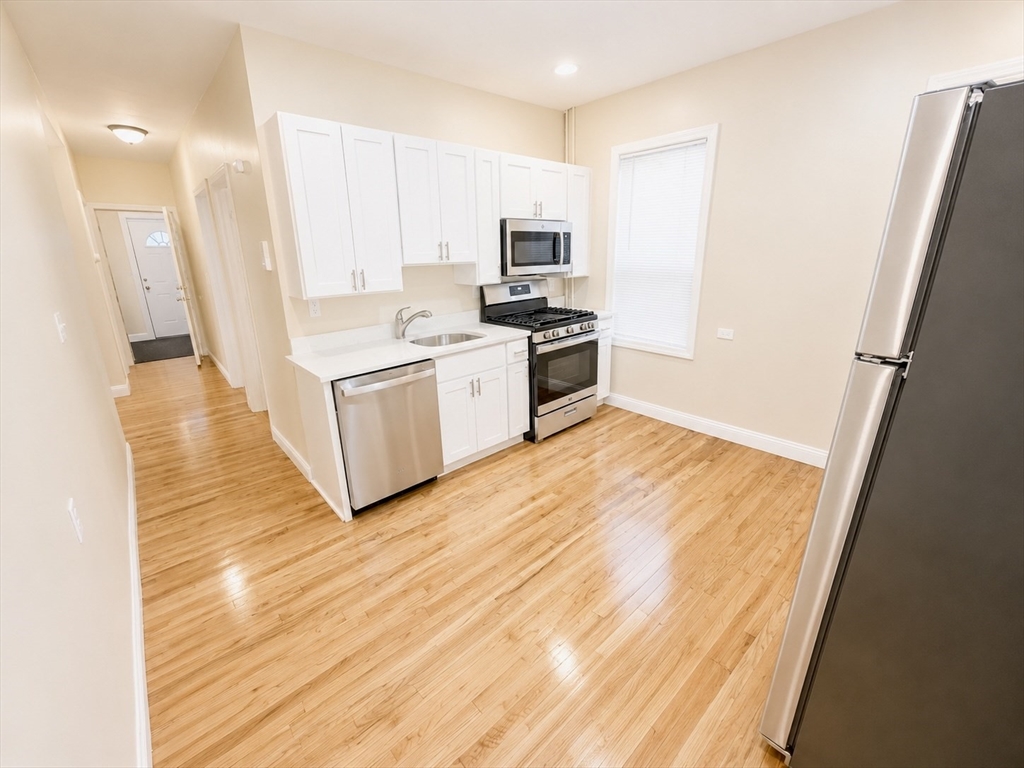 19 Dunlap Street, Unit 1 Boston, MA 02124 - Photo 8 of 9 a kitchen with granite countertop a refrigerator and a stove top oven