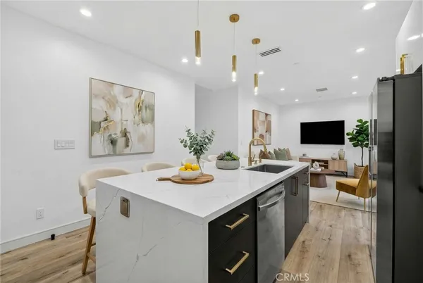 a living room with stainless steel appliances kitchen island furniture a flat screen tv and a dining table