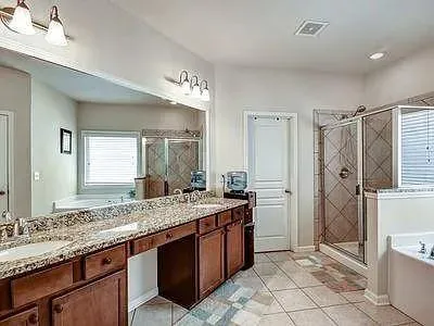 a bathroom with a granite countertop sink a toilet a mirror a vanity and bathtub