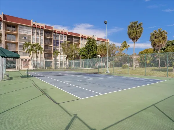 a view of a tennis ground with large trees