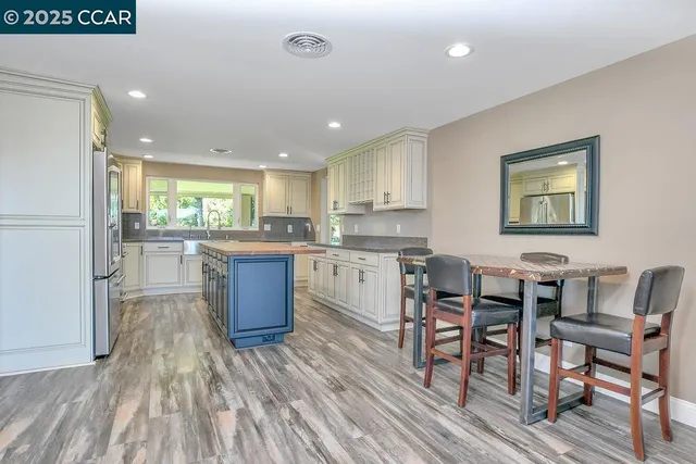 a kitchen with stainless steel appliances granite countertop a refrigerator a sink dishwasher a stove and white countertops with wooden floor