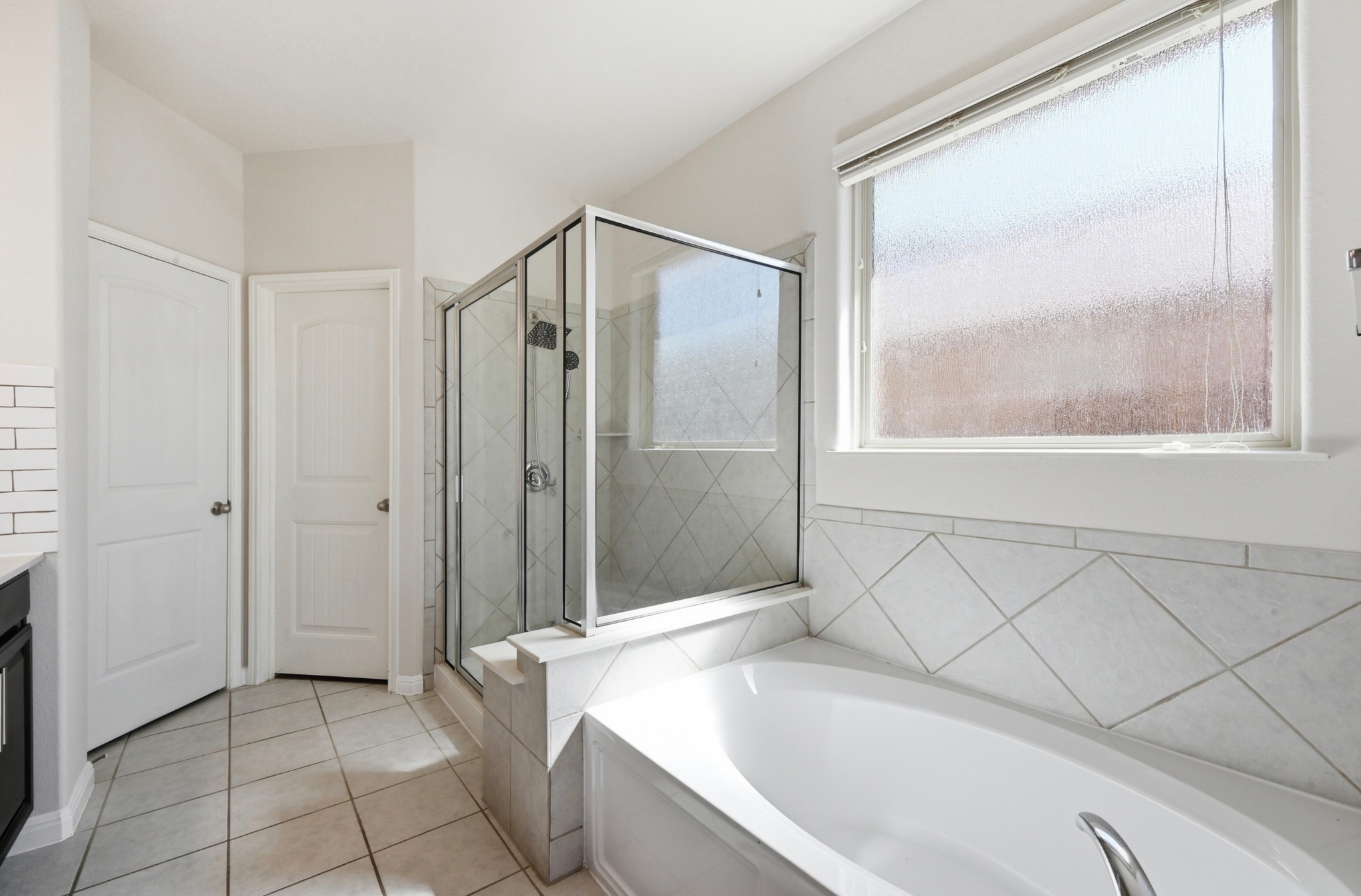351 Wincliff Drive Buda, TX 78610 - Photo 24 of 40 A well-lit bathroom features a glass-enclosed shower, a generous soaking tub, and tile flooring.