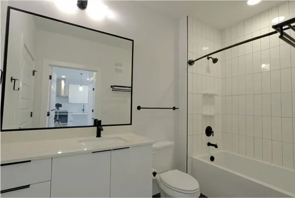 a bathroom with a bathtub shower sink vanity and toilet