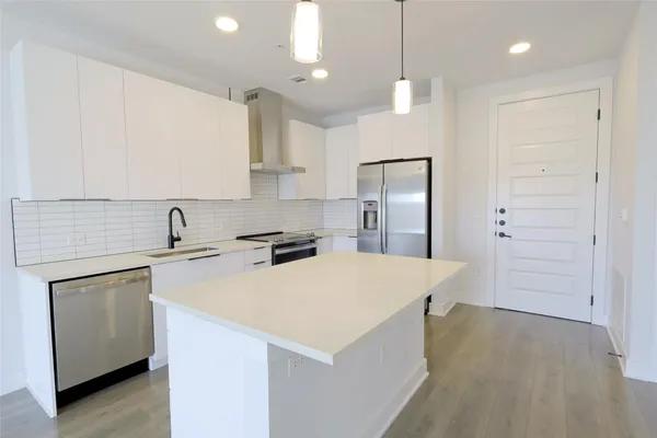 a kitchen that has a sink a center island stainless steel appliances and cabinets