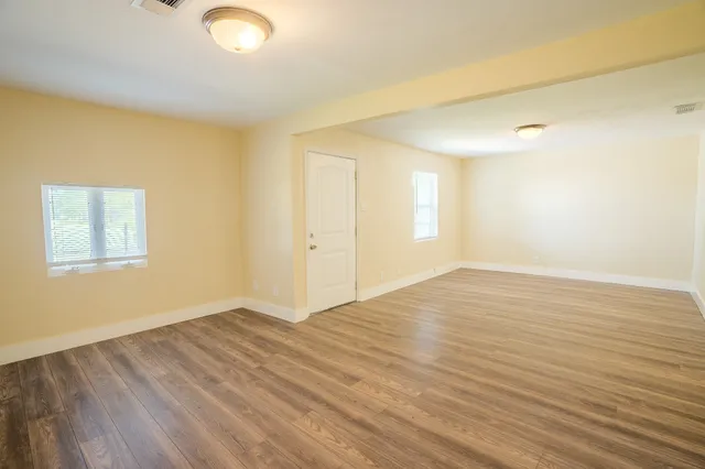 a view of empty room with wooden floor and fan