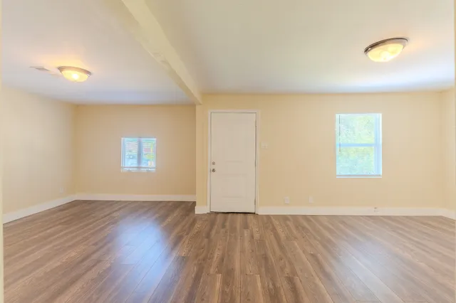 an empty room with wooden floor and windows