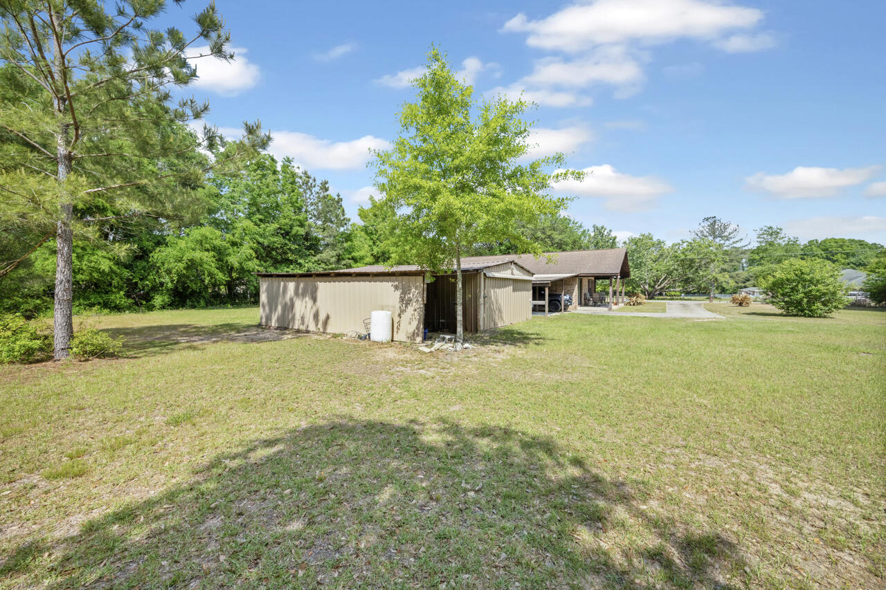 7151 Wallace Drive Pace, FL 32571 - Photo 31 of 40 a front view of a house with a garden and tree