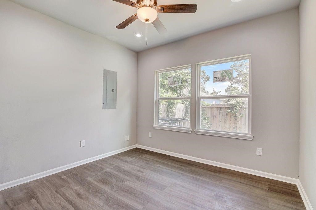5338 Rapido Road Houston, TX 77033 - Photo 7 of 9 an empty room with wooden floor chandelier fan and windows