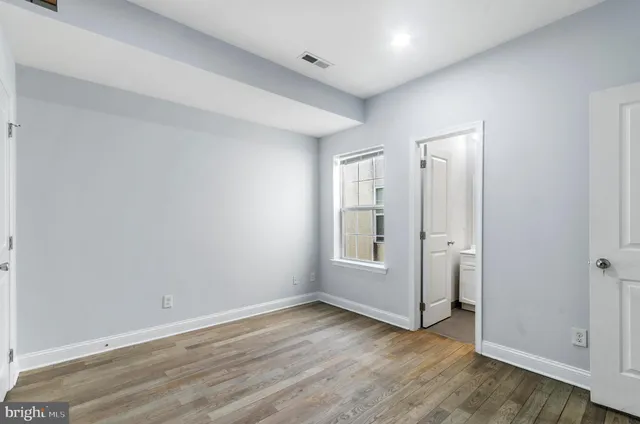 an empty room with wooden floor and white walls