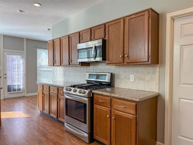 a kitchen with stainless steel appliances granite countertop a stove a sink and a microwave